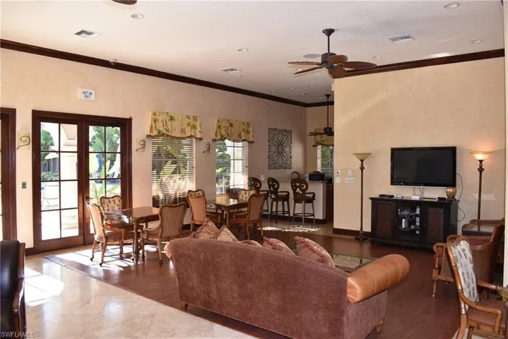 Living room featuring crown molding, ceiling fan, wood finished floors, and french doors