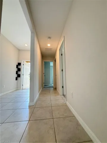 Corridor with light tile patterned floors and recessed lighting