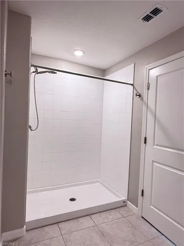 Bathroom with a shower stall and light tile patterned flooring
