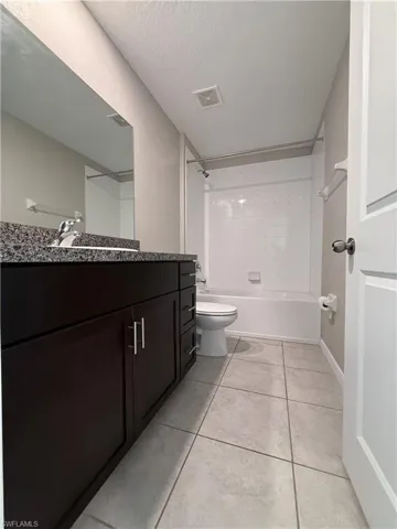 Full bath featuring shower / bathtub combination, vanity, light tile patterned flooring, and a textured ceiling
