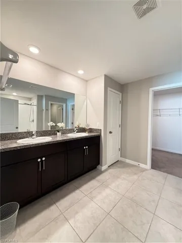 Bathroom with double vanity, light tile patterned flooring, a shower, a spacious closet, and recessed lighting