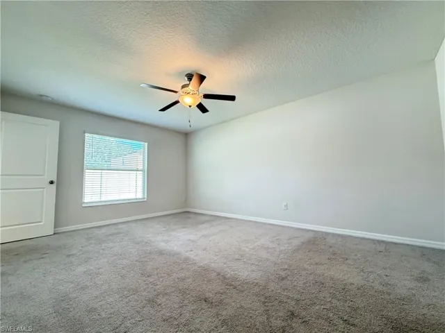 Unfurnished room with light colored carpet, a textured ceiling, and a ceiling fan