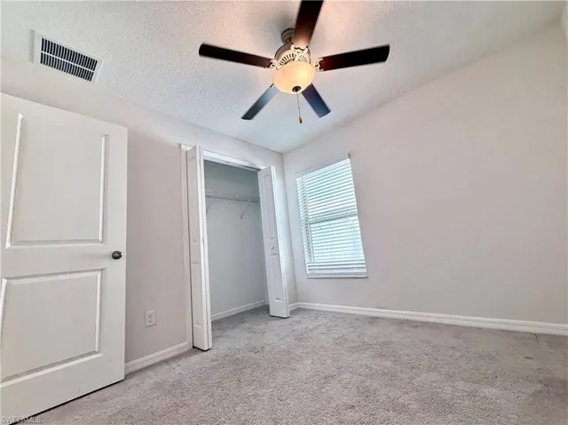 Unfurnished bedroom with a textured ceiling, carpet flooring, a ceiling fan, and a closet