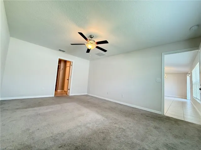 Unfurnished bedroom with light colored carpet, a textured ceiling, and ceiling fan