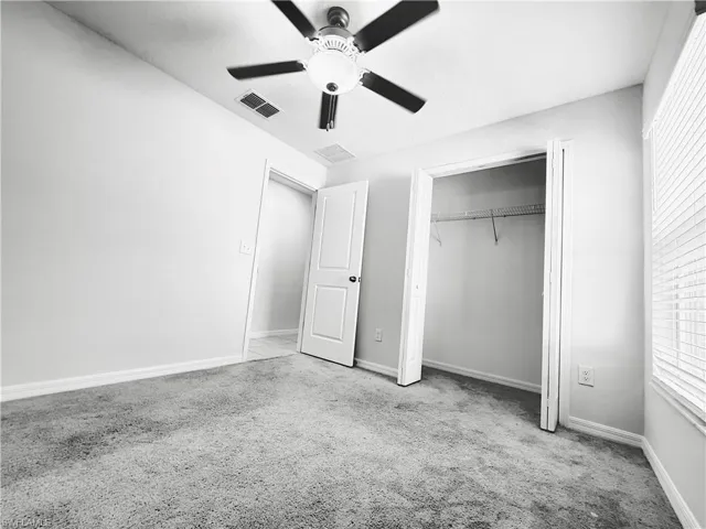 Unfurnished bedroom with light carpet, ceiling fan, and a closet