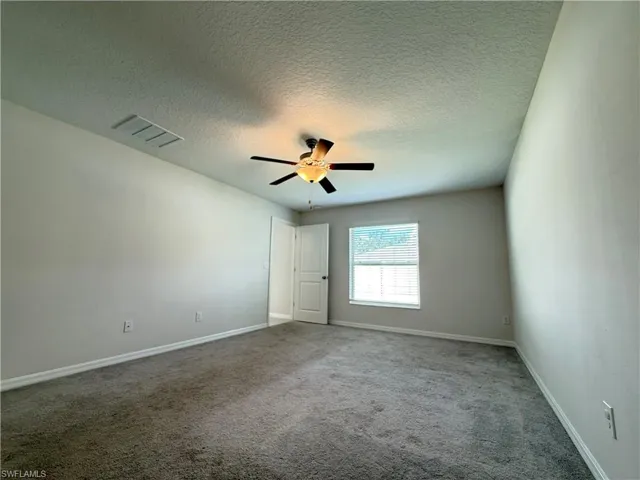 Unfurnished bedroom with a textured ceiling, carpet floors, and ceiling fan