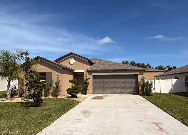 Ranch-style house with driveway, a garage, and stucco siding
