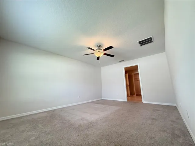 Unfurnished room with light colored carpet, a textured ceiling, and a ceiling fan