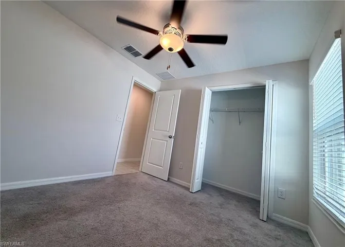 Unfurnished bedroom featuring light carpet, ceiling fan, and a closet