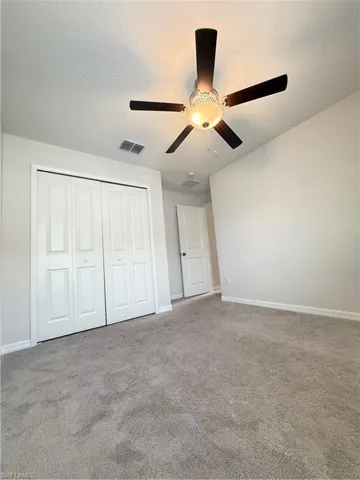 Unfurnished bedroom featuring light carpet, a closet, ceiling fan, and a textured ceiling