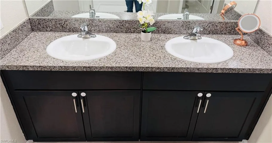Bathroom with double vanity and a textured wall
