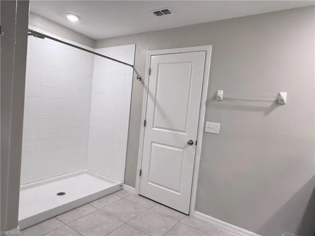 Bathroom featuring a shower stall and light tile patterned floors