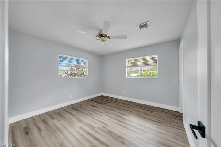 Spare room with light wood-type flooring, a ceiling fan, and healthy amount of natural light