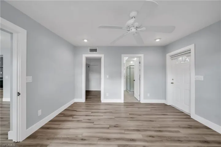 Unfurnished bedroom featuring a spacious closet, light wood-style flooring, connected bathroom, recessed lighting, and ceiling fan