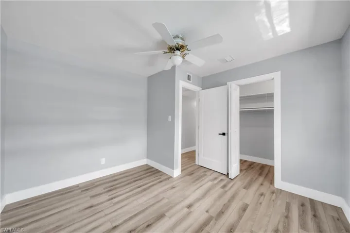Unfurnished bedroom featuring a spacious closet, light wood-type flooring, and a ceiling fan