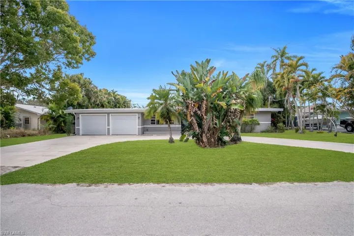 View of front of home with driveway, a front yard, and a garage