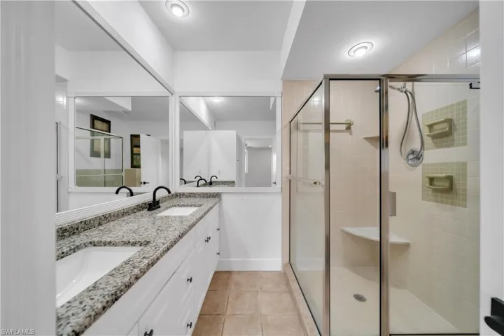 Bathroom with double vanity, a stall shower, and light tile patterned floors