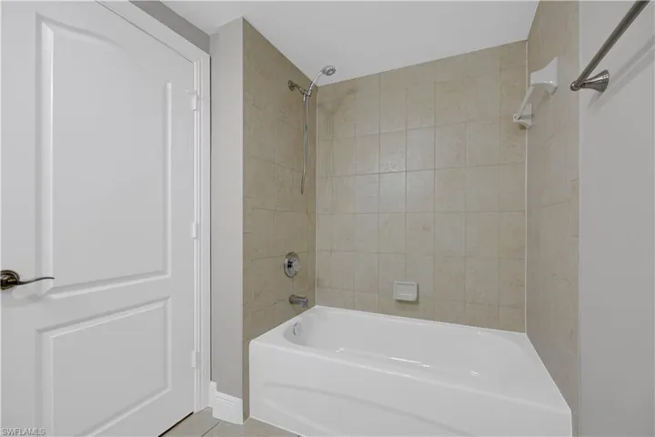 Bathroom featuring a white bathtub, chrome shower fixture, and tiled shower surround