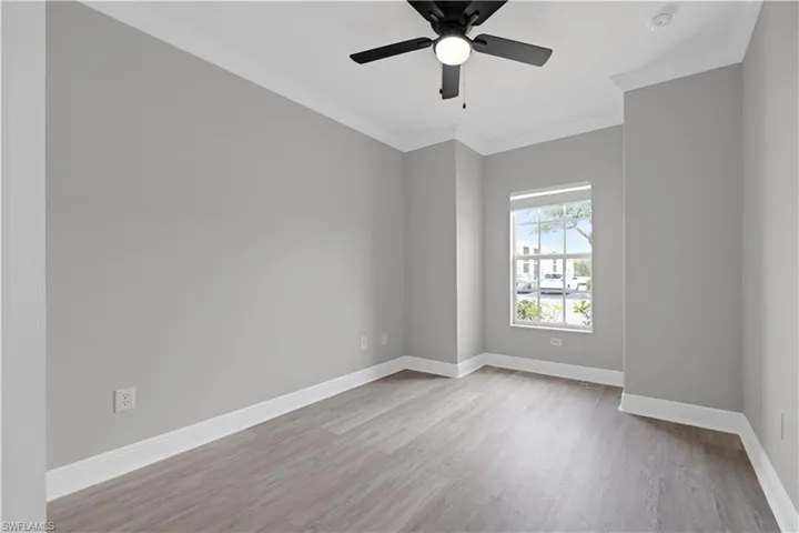 Room featuring wood-finish flooring, a ceiling fan with integrated lighting, and a double-hung window with a tree visible outside