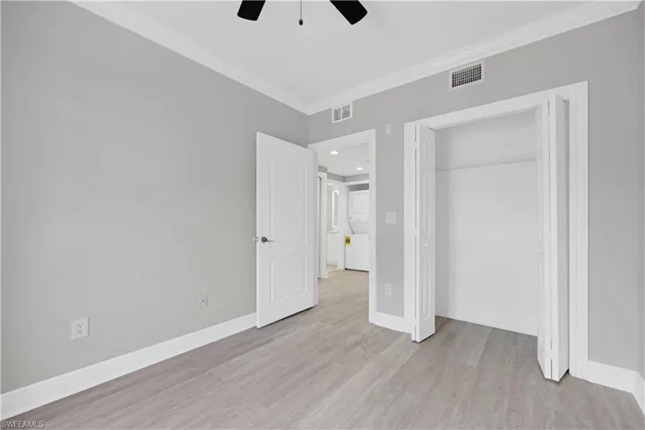 Bedroom featuring wood-finish flooring, light gray wall paint, and white crown molding