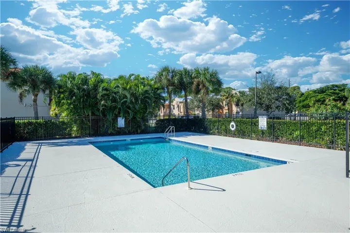 Rectangular swimming pool featuring a light blue tiled border, surrounded by a concrete deck