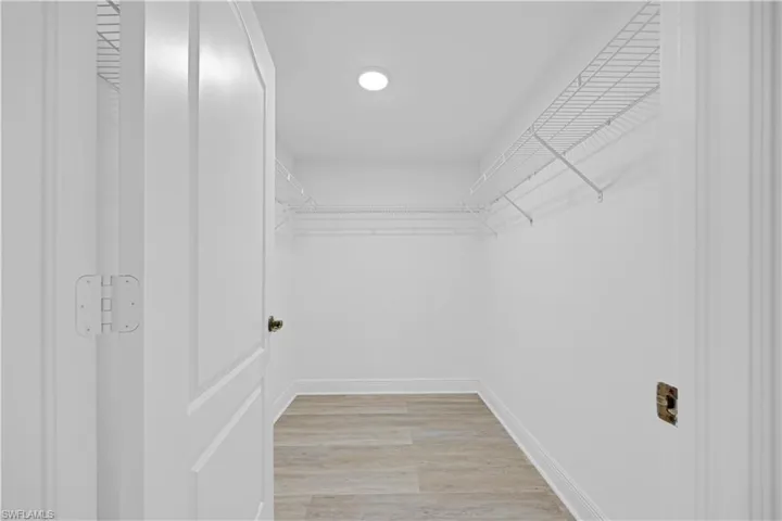 Walk-in closet featuring light wood-finish flooring, white walls, and wire shelving system