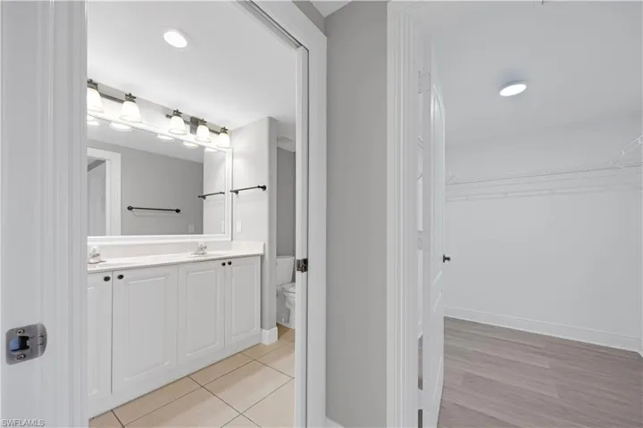 Modern bathroom featuring a double vanity with white cabinetry, light-toned countertops, and a large mirror with a multi-bulb light fixture