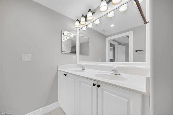 Double vanity with white cabinetry, light-toned countertop, and dual integrated sinks