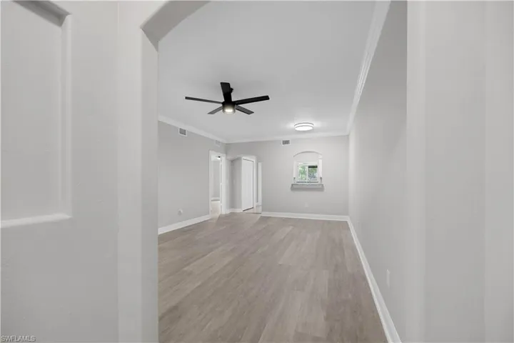Spacious interior room featuring light wood-finish flooring and crown molding