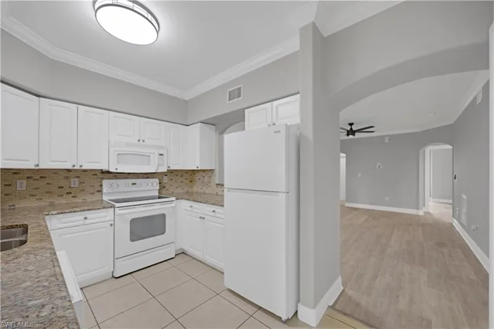 Kitchen featuring white cabinetry, a white appliance suite, granite countertops, and a tiled backsplash