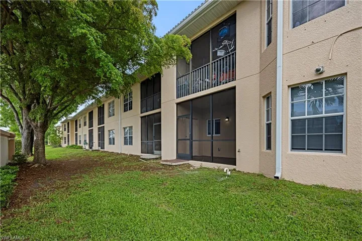 Rear exterior of a multi-story building featuring stucco siding, multiple screened-in patios, and a second-story screened balcony with metal railings