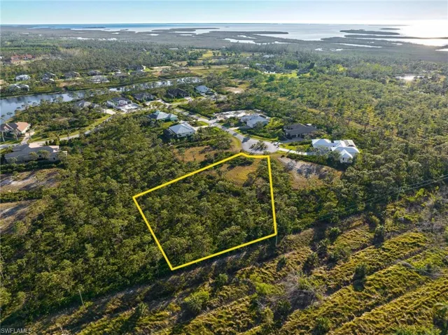 Aerial perspective of suburban area with property boundaries highlighted and a nearby body of water