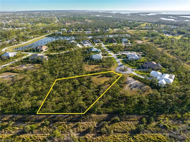 Aerial perspective of suburban area featuring a large body of water and property parcel outlined