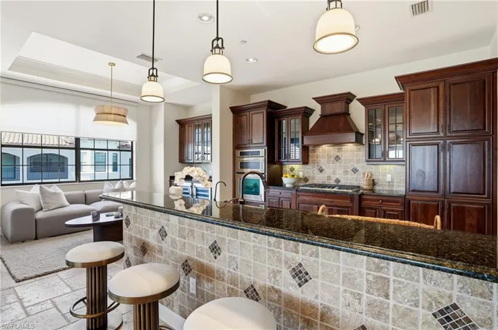 Kitchen spills over to a bright breakfast room or sitting area near the bar