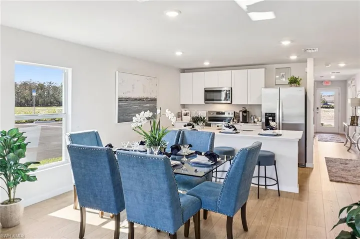 Model home. Dining space with light wood-style floors and recessed lighting