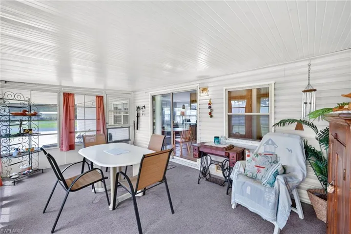Enclosed patio featuring white horizontal siding, a textured white ceiling, carpeted flooring, multiple windows, and a sliding glass door