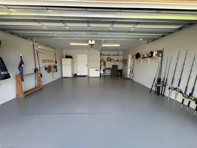 Garage featuring a garage door opener, water heater, and white fridge
