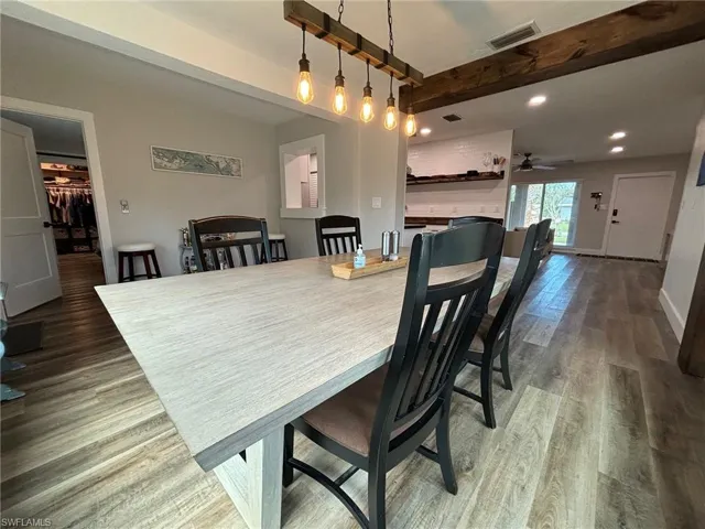 Dining room featuring dark wood-type flooring, beam ceiling, and ceiling fan