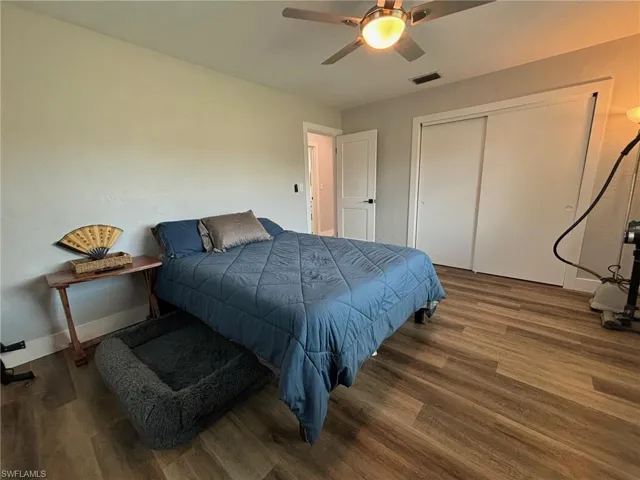 Bedroom with dark hardwood / wood-style floors, a closet, and ceiling fan