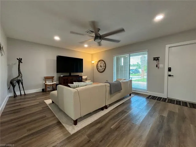Living room featuring dark wood-type flooring and ceiling fan