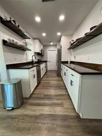 Kitchen featuring sink, refrigerator, stainless steel dishwasher, white cabinets, and dark hardwood / wood-style floors