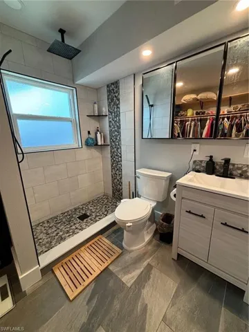 Bathroom with toilet, vanity, and a tile shower