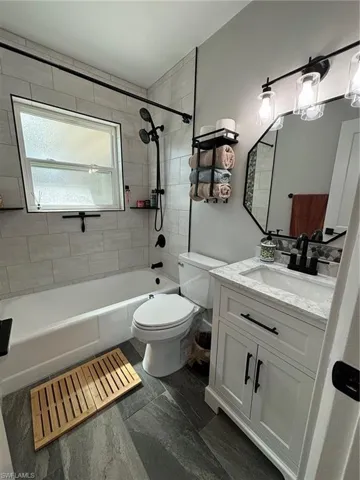 Full bathroom with tiled shower / bath, vanity, and toilet