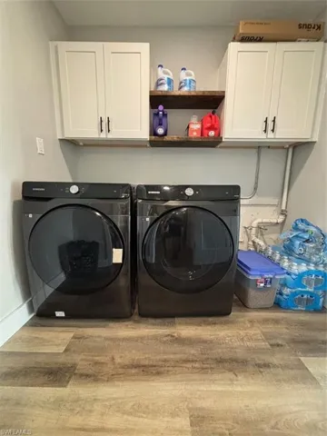 Laundry room with washer and dryer, light hardwood / wood-style floors, and cabinets