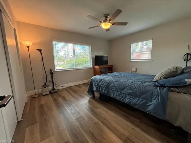 Bedroom with multiple windows, ceiling fan, and dark hardwood / wood-style flooring