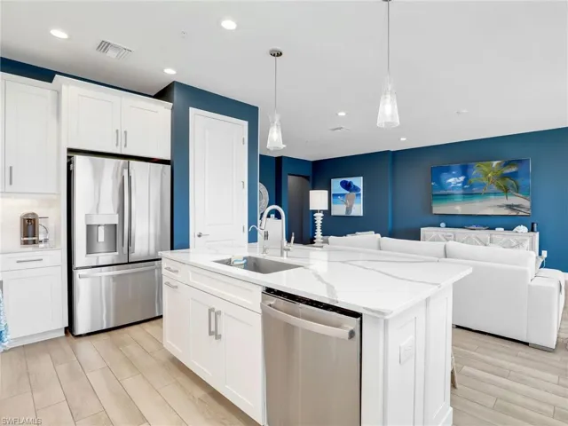 Kitchen featuring a sink, visible vents, open floor plan, appliances with stainless steel finishes, and wood tiled floor