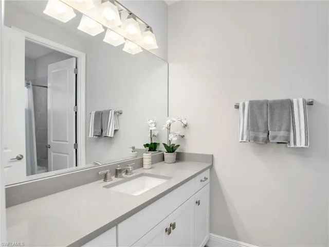Full bathroom with baseboards, walk in shower, and vanity