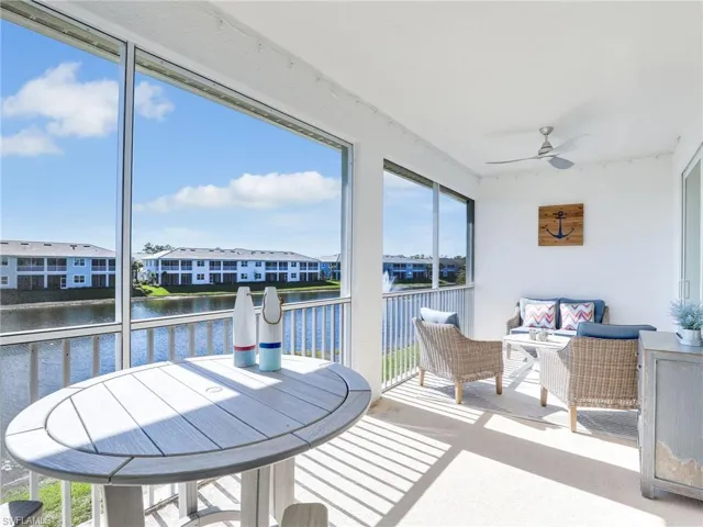 Sunroom featuring a water view, plenty of natural light, a residential view, and ceiling fan