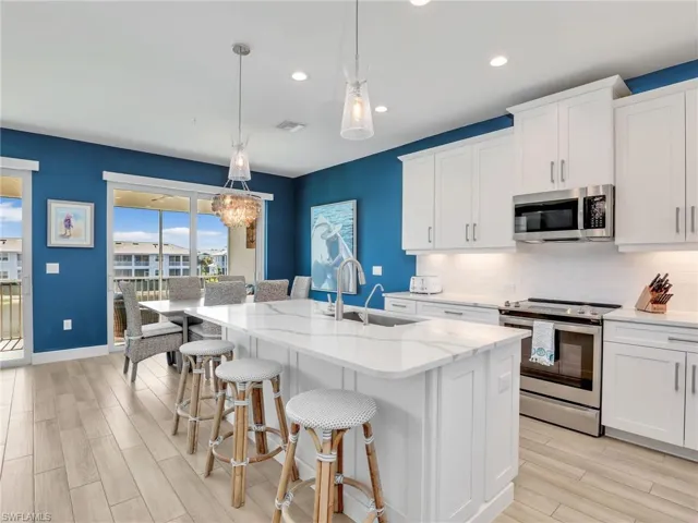 Kitchen featuring stainless steel appliances, backsplash, a sink, and white cabinetry
