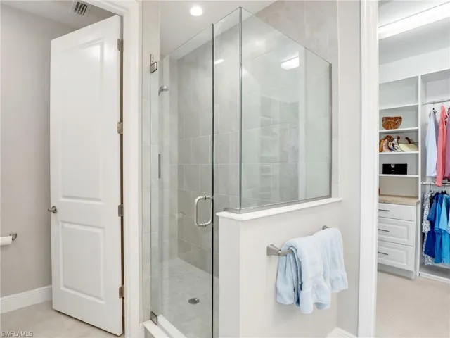 Full bath with a stall shower, visible vents, baseboards, tile patterned flooring, and a spacious closet